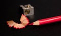 Red pencil with pencil shavings and pencil sharpener up close Royalty Free Stock Photo