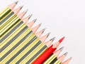 Red pencil standing out from crowd of black pencils against white background. Royalty Free Stock Photo