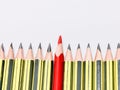 Red pencil standing out from crowd of black pencils against white background. Royalty Free Stock Photo