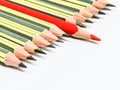Red pencil standing out from crowd of black pencils against white background. Royalty Free Stock Photo