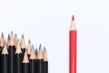 Red pencil standing out from crowd of plenty identical black fellows Royalty Free Stock Photo