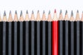 Red pencil standing out from crowd of plenty identical black fellows Royalty Free Stock Photo