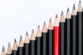 Red pencil standing out from crowd of plenty identical black fellows Royalty Free Stock Photo