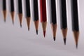 Red pencil stands out from crowd of many identical black pencils