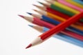 Red pencil on top of row of coloured pencils on white background Royalty Free Stock Photo
