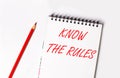 Red pencil and white notepad with the text KNOW THE RULES Royalty Free Stock Photo