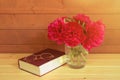 Red peonies in vase, book and glasses on wooden table. Selective focus. Royalty Free Stock Photo