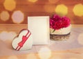 Red peony flowers in wicker basket, heart shape gift box and white frame on wooden table Royalty Free Stock Photo