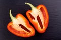 Red pepper cut into two parts on dark stone Royalty Free Stock Photo