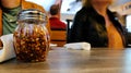 Red pepper flakes in a glass shaker on a wooden table in a pizza parlor. Royalty Free Stock Photo