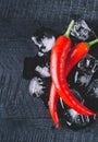 Red pepper and ice on a black wood background, fresh hot food on vintage table, freeze cold cube ice mock up top view