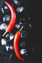 Red pepper and ice on a black wood background, fresh hot food on vintage table, freeze cold cube ice mock up top view