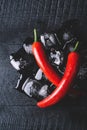 Red pepper and ice on a black wood background, fresh hot food on vintage table, freeze cold cube ice, mockup top view