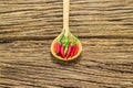 Red peppers in wooden spoon on wooden background