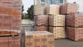 Red perforated bricks with rectangular holes on wooden pallets in an open-air warehouse ready for sale. New bricks on pallets at a