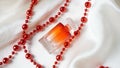 Red perfume bottle and necklace on the white silk background Royalty Free Stock Photo
