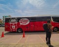 Red Peruhop Bus with tourist standing in front of it, llama cartoon on the side