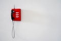 A red phone with a black handset and an antenna hangs on a white wall. Phone number for calling emergency services Royalty Free Stock Photo