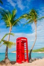 Red phone booth in Dickenson`s bay Antigua. Beautiful landscape with a classic phone booth on the white sandy beach in Royalty Free Stock Photo