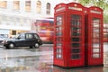 Red Phone cabines in London and vintage taxi.Rainy day. Royalty Free Stock Photo