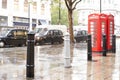 Red Phone cabines in London and vintage taxi.Rainy day. Royalty Free Stock Photo