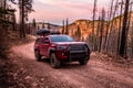 Red pickup with overland offroad equipment on rough dirt road in southern Utah desert