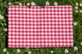 Red picnic blanket. Red checkered picnic cloth on a flowering meadow with daisy flowers. Beautiful backdrop for your product