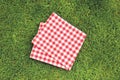 Red picnic folded towel on green grass top view, checked cloth flat lay. Food advertisement display Royalty Free Stock Photo