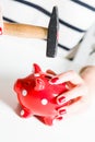 Red piggy bank and hammer held by woman