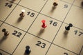 Red pin on a calendar square, highlighting an important day for business deadlines. Royalty Free Stock Photo