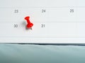 Red pin push on day 31 of end month on white calendar. Mark this day as salary date. Concept of meeting appointment reminder