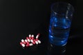 Red and pink antibiotic capsule and glass of water