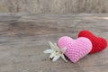 Red and pink knitting hearts with Millingonia on the wooden rough table. Background of the rock wall. Sun light shines on the fram