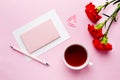 Red-pink objects. Cup of tea, carnation flowers Notepad for text on pastel pink background. Copy space. Top view Flat lay Royalty Free Stock Photo