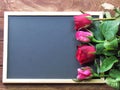 Red and pink roses placed on the blackboard on the wooden background