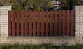 Red planks in a stone white fence around a house