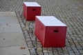Red plastic benches in the shape of blocks with handles. The square is paved with granite cubes. sandy surface. built around a squ