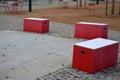 Red plastic benches in the shape of blocks with handles. The square is paved with granite cubes. sandy surface. built around a squ