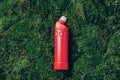 Red plastic bottle of cleaning product, household chemicals or liquid laundry detergent on green grass, moss background Royalty Free Stock Photo