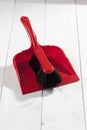 Red plastic brush and dustpan on white wooden background Royalty Free Stock Photo