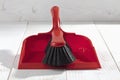 Red plastic brush and dustpan on white wooden background Royalty Free Stock Photo