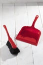 Red plastic brush and dustpan on white wooden background Royalty Free Stock Photo