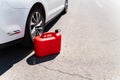 A red plastic can is in the middle of the road next to a white car. Refueling problems Royalty Free Stock Photo