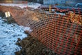 Red plastic caution fence with mesh during excavation or repair work in winter