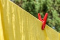 The red plastic clothespin is on the clothesline with yellow cot Royalty Free Stock Photo