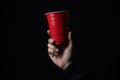 Red plastic cup with a hand in the dark. Royalty Free Stock Photo