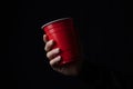 Red plastic cup with a hand in the dark. Royalty Free Stock Photo