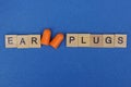 Red plastic ear plugs and word made of wooden letters Royalty Free Stock Photo