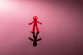 Red plastic figure of a man standing on a mirror pink surface Royalty Free Stock Photo