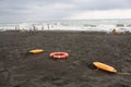 Red plastic floatation rescue devices and sunbeds on beach. the weather is dull